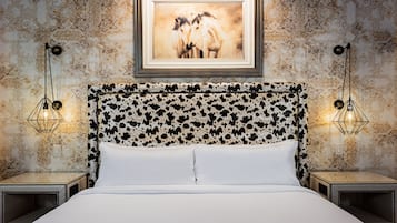 A bed with a patterned headboard, two bedside lamps, and a framed picture above the bed.