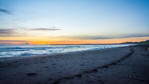A beach with a clear sky and a sunset. - The Goddess Garden (Cahuita)