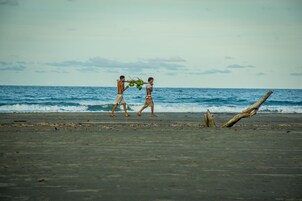 Dos personas caminando en la playa, con el océano al fondo.