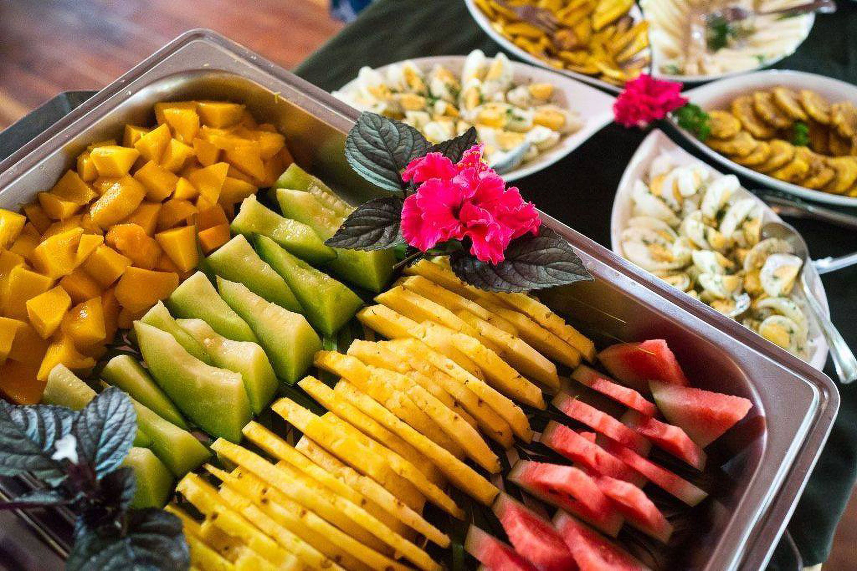 A buffet with various fruits including mangoes, cantaloupes, and watermelon.