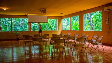 A room with large windows, chairs arranged in rows, and a projector screen.