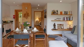 A modern living room with a dining area, a sofa, and a bookshelf.