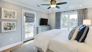 Un dormitorio con cama, ventilador de techo, televisión y obras de arte en las paredes.