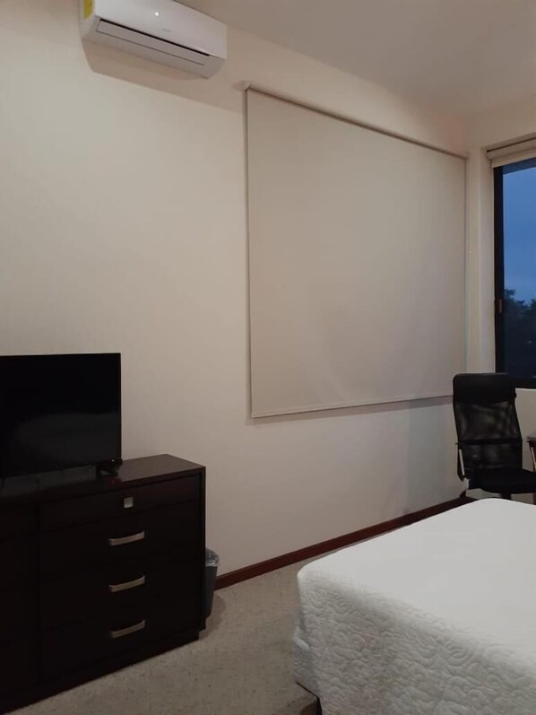 A hotel room with a bed, a TV on a dresser, a chair, and a window. - Hotel Candelero (Yuriria)