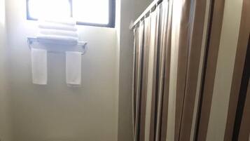 A small bathroom with a toilet, a trash bin, and a shower curtain.