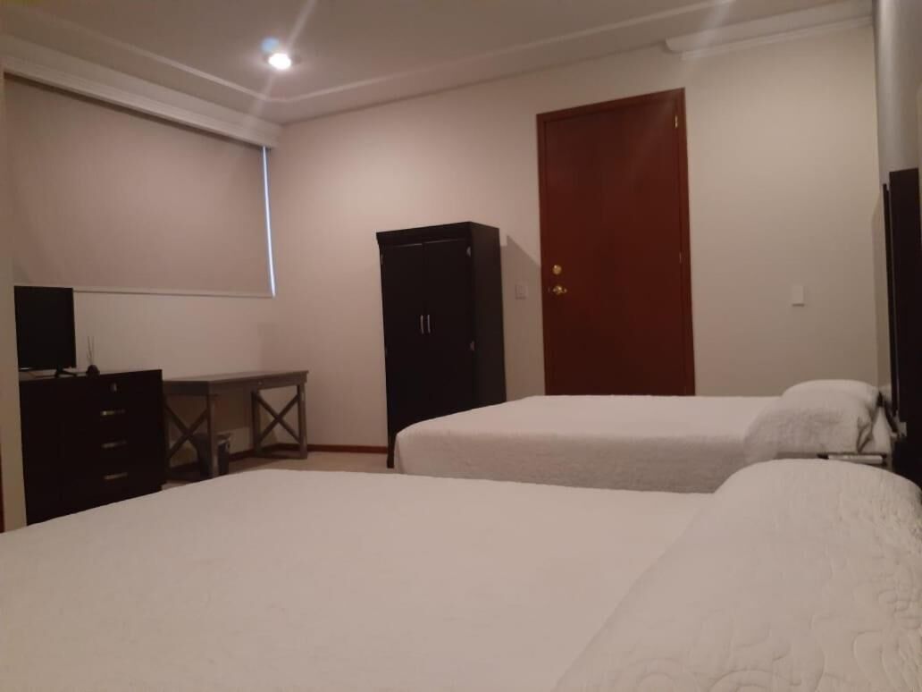 Une chambre avec deux lits, un bureau, une armoire et une porte.