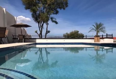 Una piscina al aire libre, sombrillas