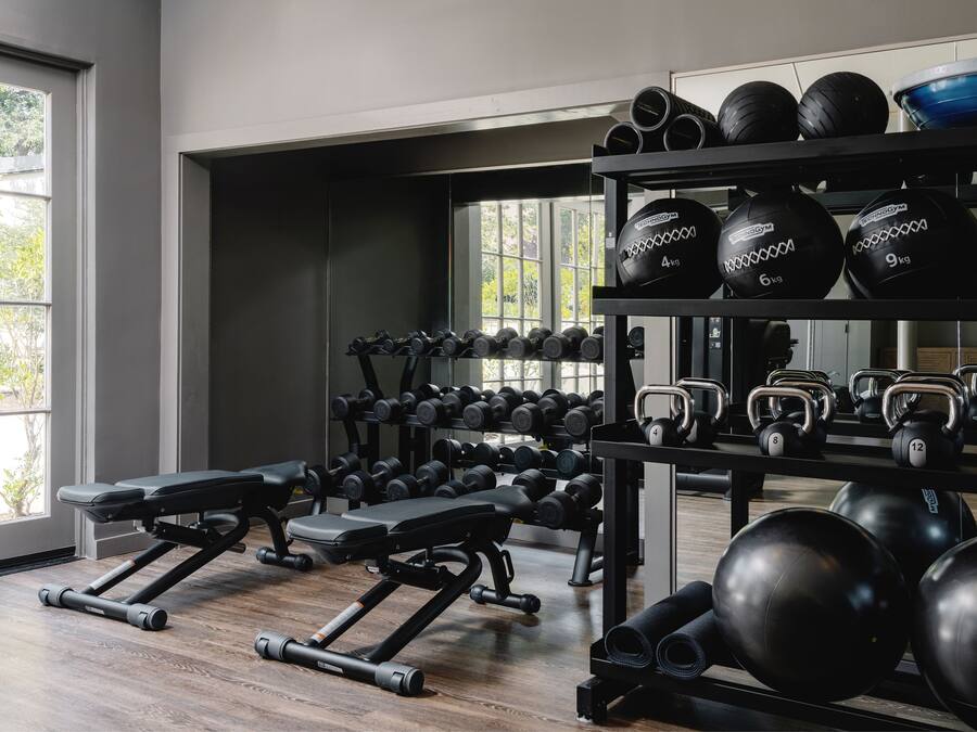 Ett gym med utrustning för styrketräning, träningsbänkar och träningsbollar.