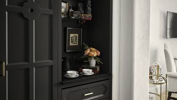 Un meuble noir avec des étagères, des tiroirs et une petite table sur laquelle est posé un vase de fleurs.