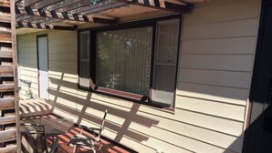 Une terrasse couverte avec un sol en briques, une chaise en métal et une table.