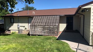 Une maison avec un toit en pente, une cour clôturée et un petit porche.