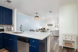 A modern kitchen with blue cabinets, a white countertop, and a built-in dishwasher.