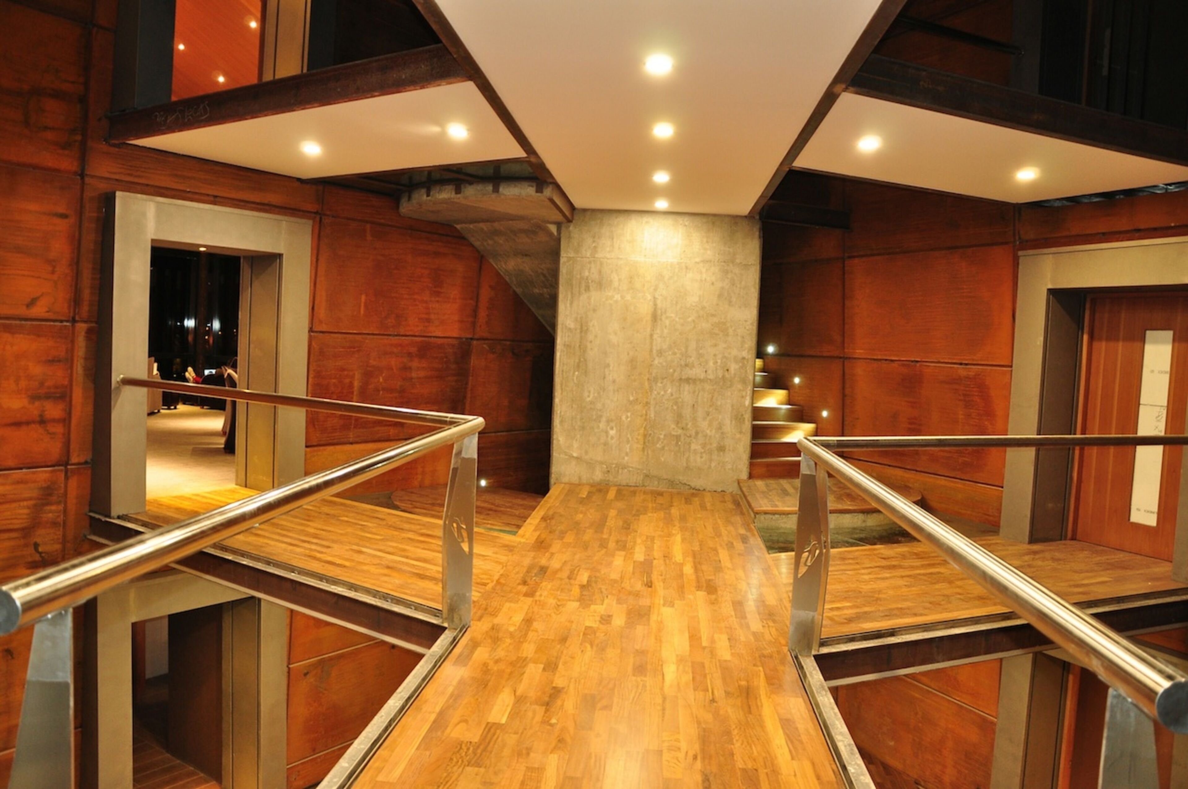 A modern interior with wooden flooring, metal railings, and a central column.