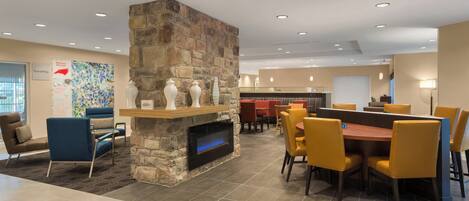 A modern dining area with a stone fireplace, yellow chairs, and a large table.