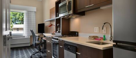 A modern kitchen with built-in appliances, a dining area with a chair, and a view of the outdoors.