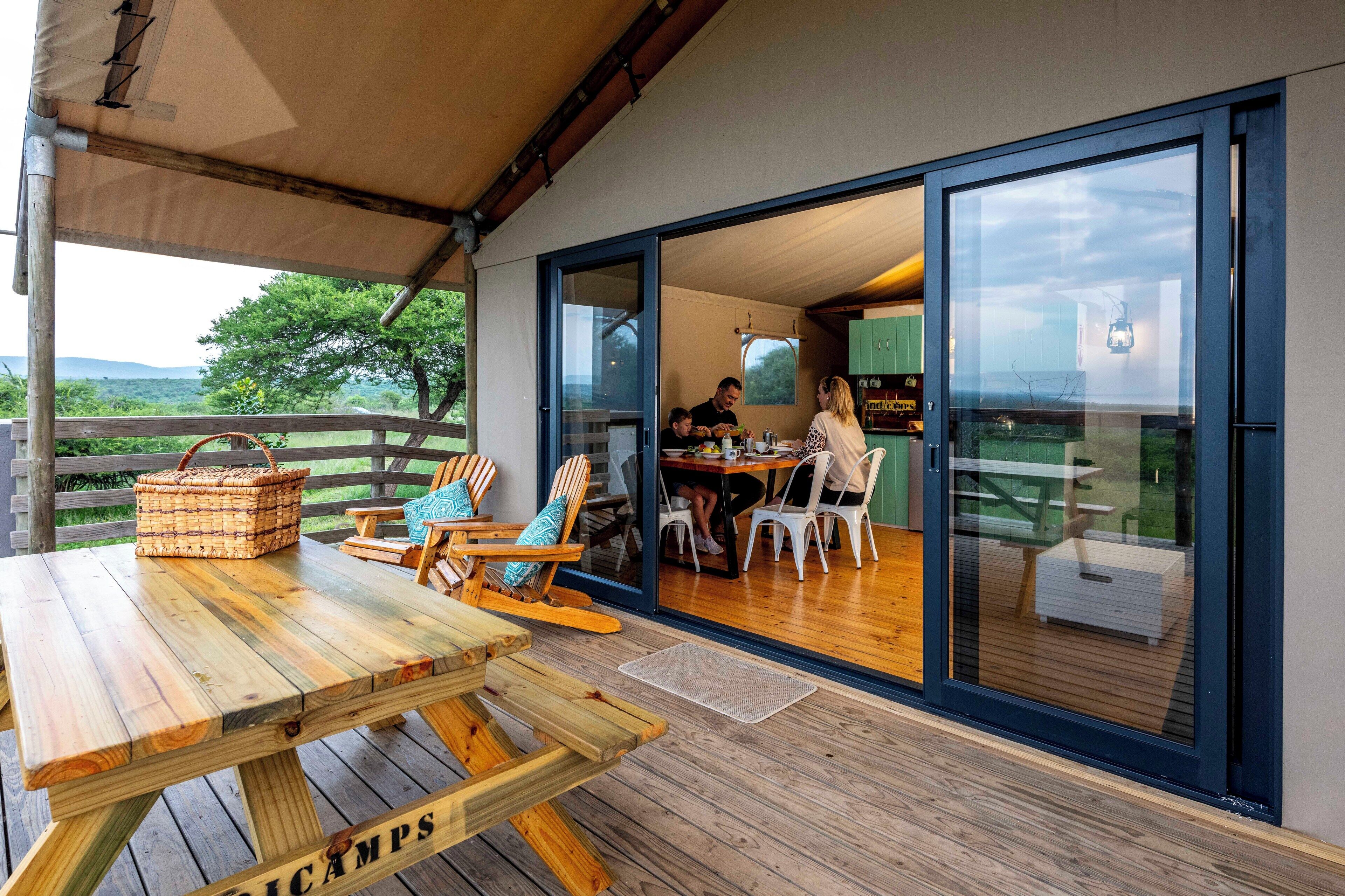 Un espace de restauration en plein air avec des tables et des chaises en bois, un panier en osier et une vue sur le paysage.