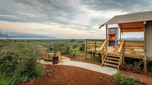 A wooden deck with a stone pathway leading to a tented area with a fireplace. - Africamps at White Elephant Safaris (Pongola)