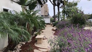 Um caminho de jardim que leva a uma casa com fachada branca e um caminho de pedra.