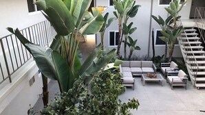 Estar alpendre coberto com um conjunto de sofás, uma escadaria e diversas plantas.