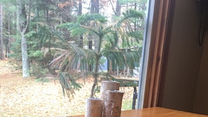 A wooden table with three candles and two chairs in a room with a view of trees and a window. - Cute, rustic cabin in Side Lake, No WiFi (Side Lake)