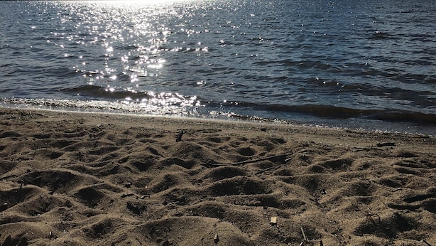 A beach with a sandy foreground and a calm sea. - Cute, rustic cabin in Side Lake, No WiFi (Side Lake)