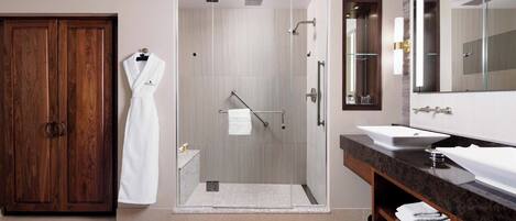 A modern bathroom with a glass-enclosed shower, a wooden wardrobe, a vanity with two sinks, and a large mirror.