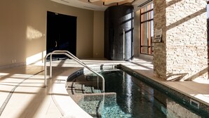 Una piscina interior con pared de piedra y techo de madera.