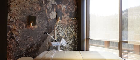 Une chambre avec un lit, une petite table, une horloge murale et une fenêtre donnant sur un paysage agréable.