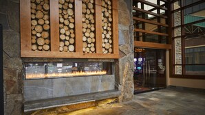 A stone fireplace with a fire, surrounded by stone walls and a wooden log display. - Monarch Casino Resort Spa Black Hawk (Black Hawk)