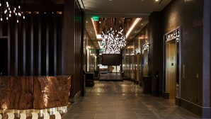 A modern hotel lobby with a reception desk, a large chandelier, and a reception area. - Monarch Casino Resort Spa Black Hawk (Black Hawk)