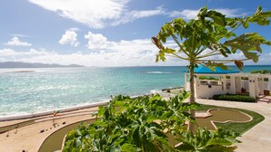 A coastal view with a clear sky, a beach, and a building with a blue roof. - Villa Anguillitta (Blowing Point)