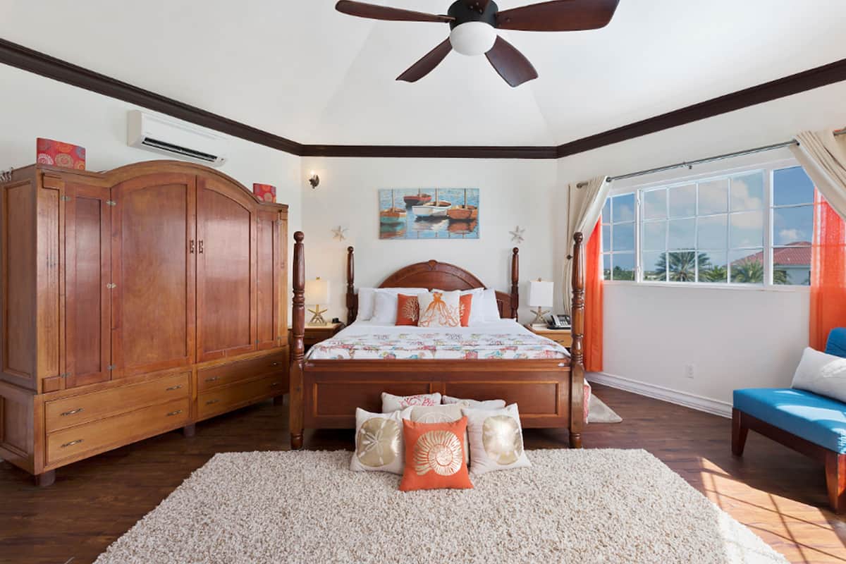 A bedroom with a large bed, wooden wardrobe, and a window with curtains.