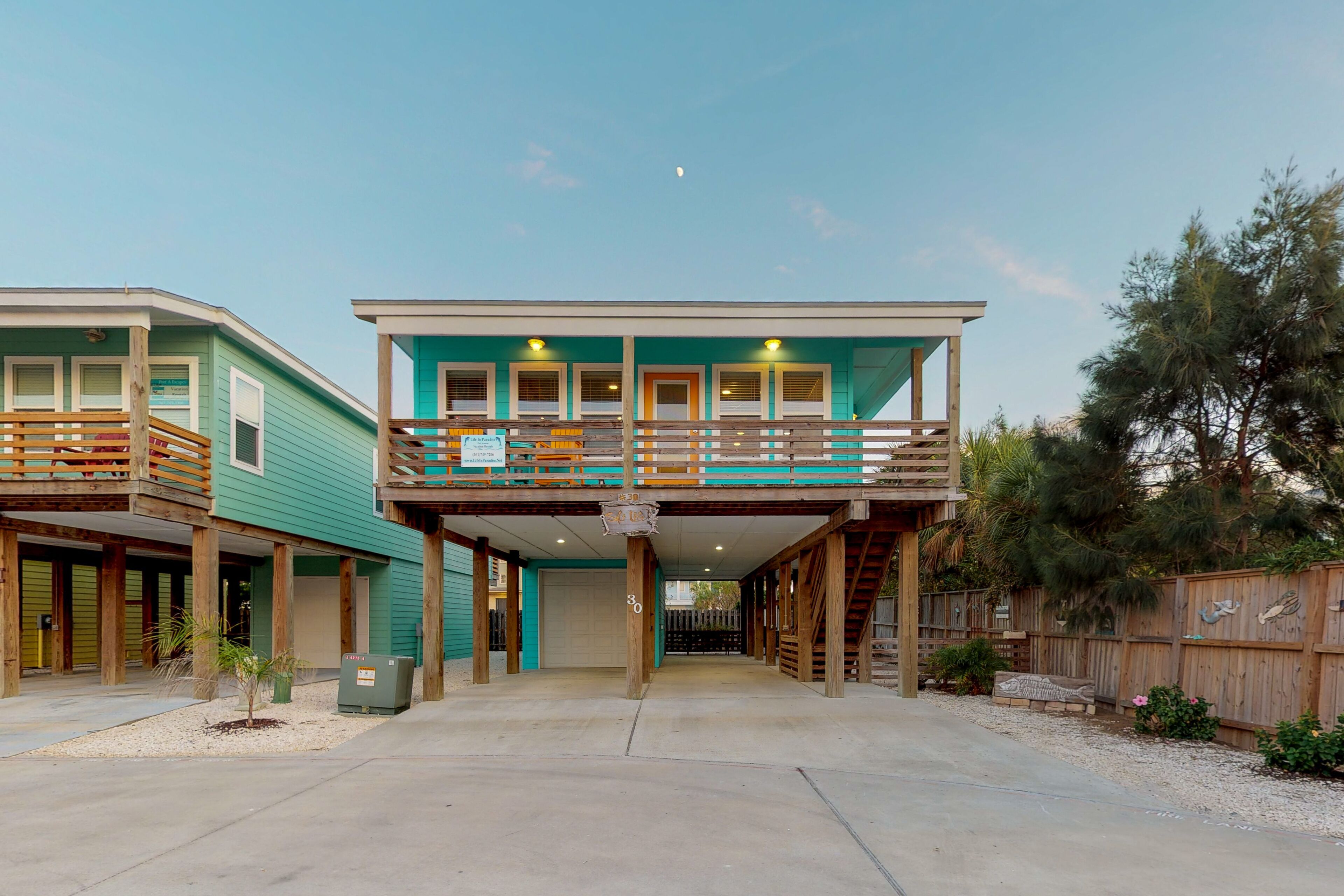 A two-story building with a balcony, a garage, and a wooden fence.
