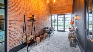 Una stanza spaziosa con pareti in mattoni a vista, soffitto in legno e un'ampia finestra che offre vista sull'esterno.
