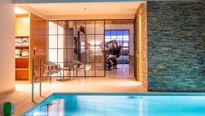 Area piscina interna moderna, con vista diretta su una sala da pranzo e un muro in pietra.