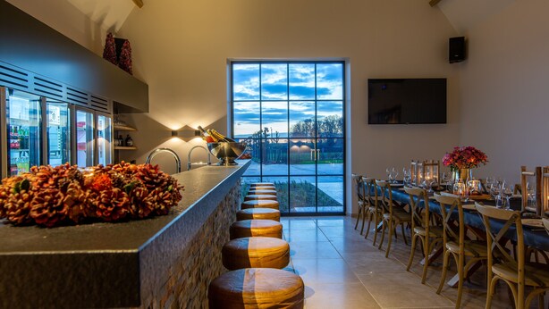 Una cucina moderna con un'ampia zona bar, una grande finestra vista panoramica e un'area pranzo con sedie in legno e tavolo imbandito per sei persone.
