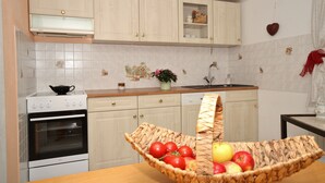 Una cocina con armarios blancos, una estufa y un lavabo. Hay una cesta de fruta en la encimera.