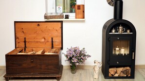 Un cofre de madera con leña, un jarrón con flores y un hogar de leña negro con chimenea.