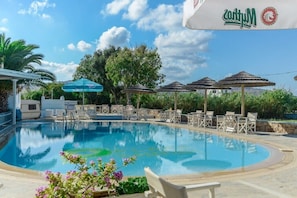 En säsongsöppen utomhuspool, parasoller och solstolar