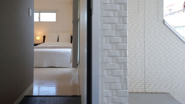 Ein Hotelzimmer mit einem Bett, einem Nachttisch, einem Fenster und einer weißen Ziegelwand.