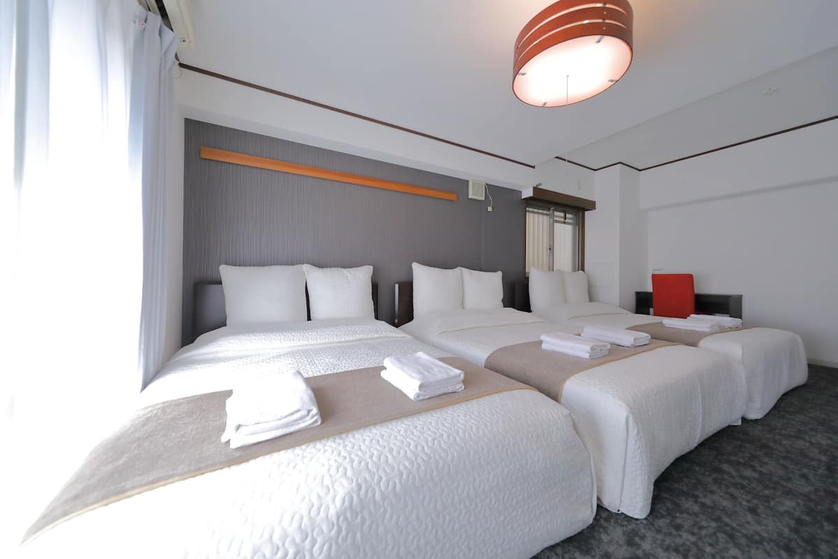 A hotel room with two beds, a large mirror, and a red accent wall.