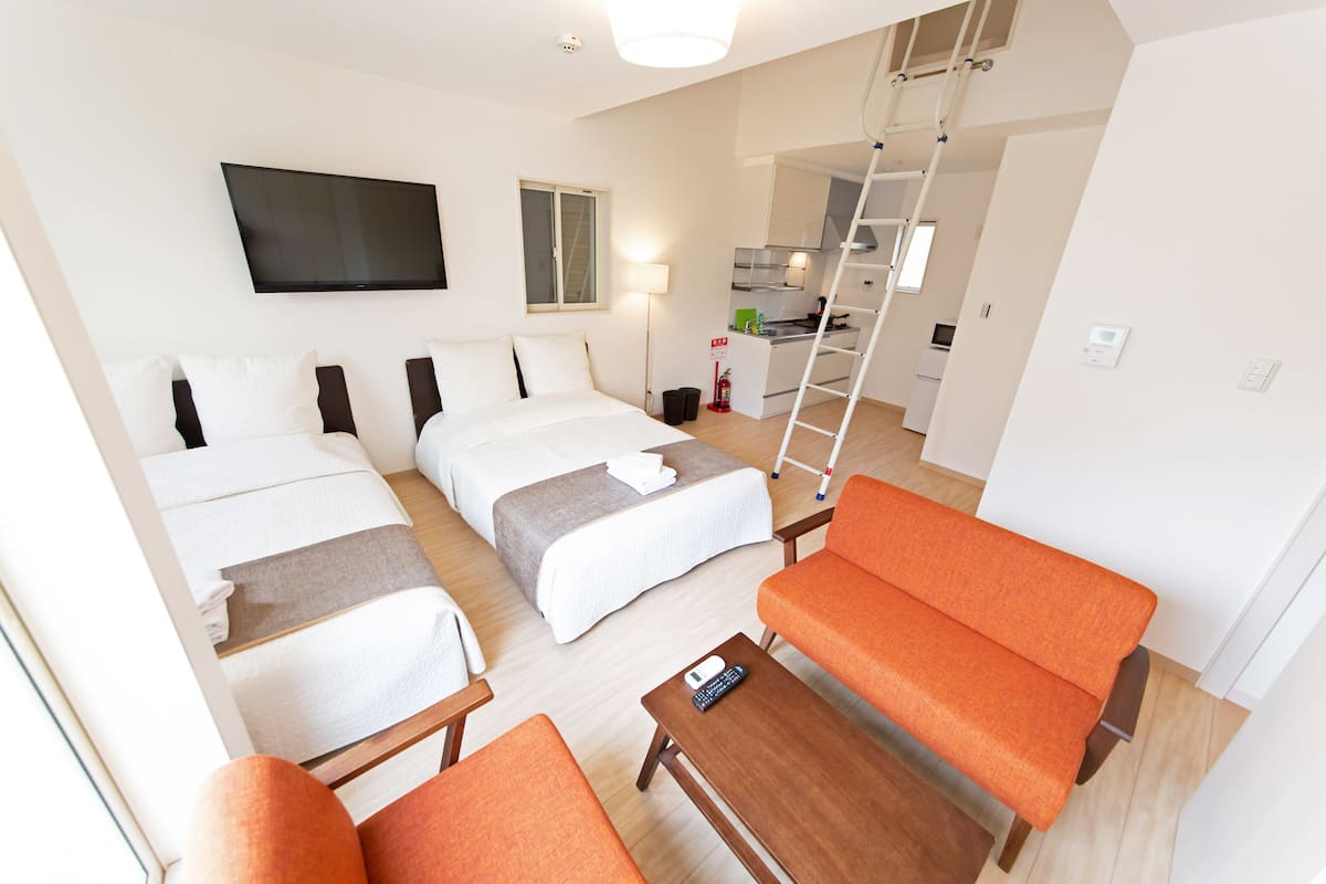 A hotel room with two beds, a TV, a desk, and a chair.