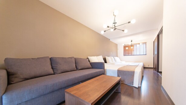 Een moderne woonkamer met een grijze bank, een houten salontafel en een blauwe fauteuil.