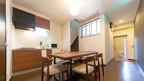 Een eethoek met een houten tafel en stoelen, een magnetron en een fornuis in de keuken.