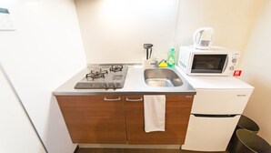 Een compacte keuken met een gasfornuis, spoelbak en een magnetron.