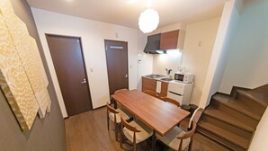 Een kleine keuken met een houten eettafel en stoelen, een magnetron en een fornuis.