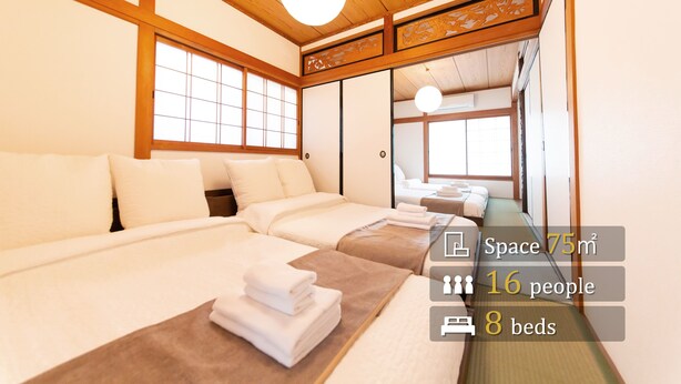 Ein traditionell gestaltetes Hotelzimmer im japanischen Stil mit acht Betten, einem Tatami-Boden und verschiebbaren Türen.