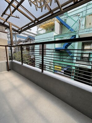 Un balcon doté d’une rambarde en métal, donnant sur une zone industrielle avec des bâtiments et des escaliers.