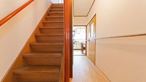 Eine Holztreppe mit Handlauf, die zu einem Raum mit einer Küche im Hintergrund führt.