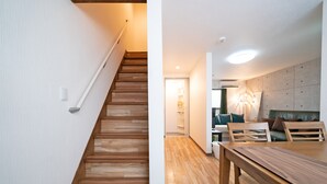 A staircase with wooden steps leading to a room with a dining table and chairs. - TWS Morinomiya (Osaka)
